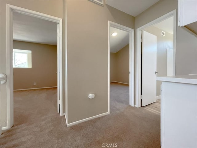 hallway with light colored carpet and baseboards