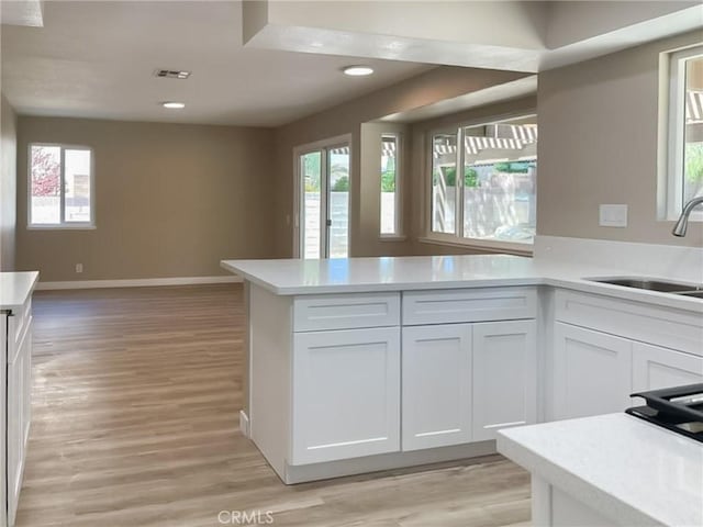 kitchen with a sink, white cabinets, light countertops, and recessed lighting