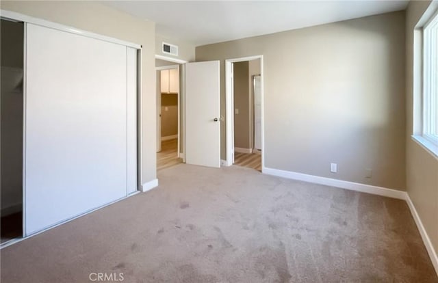 unfurnished bedroom with carpet, a closet, and baseboards