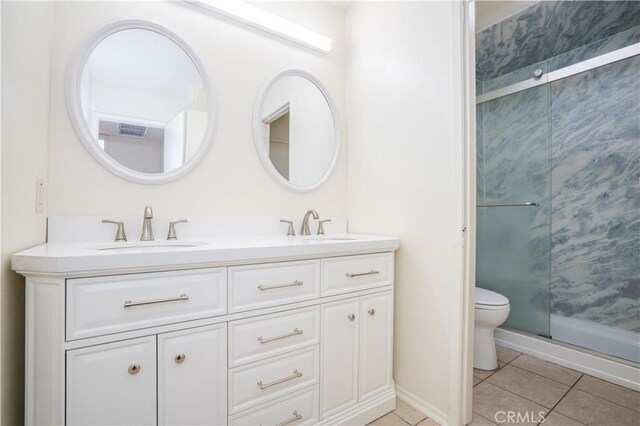 bathroom with a stall shower, tile patterned floors, double vanity, and a sink
