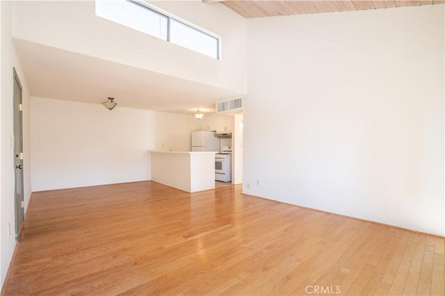 unfurnished living room featuring a towering ceiling, wooden ceiling, light wood-style floors, and visible vents