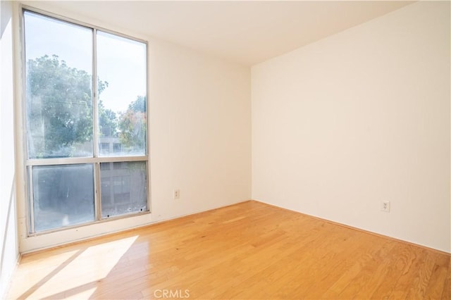 unfurnished room with floor to ceiling windows and wood finished floors