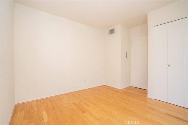 unfurnished bedroom featuring visible vents, a closet, and light wood-style floors