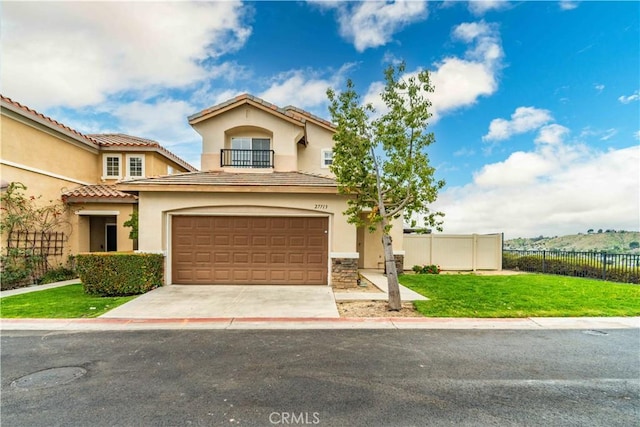 mediterranean / spanish home featuring a front yard, concrete driveway, stucco siding, fence, and a garage