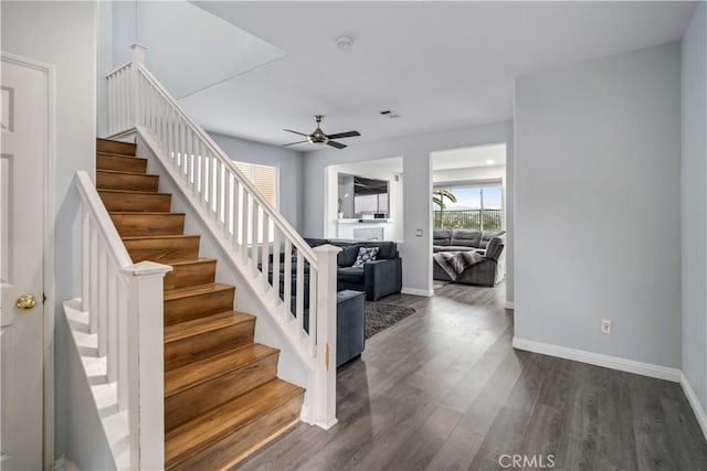 stairway with wood finished floors, baseboards, and ceiling fan