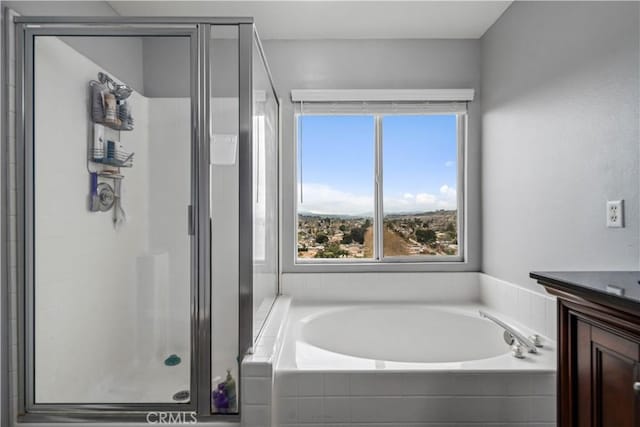 bathroom featuring a stall shower, vanity, and a garden tub