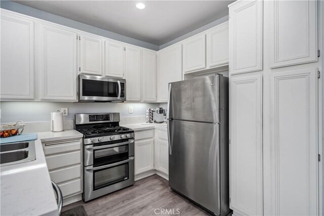 kitchen with light wood-style flooring, recessed lighting, appliances with stainless steel finishes, white cabinetry, and a sink