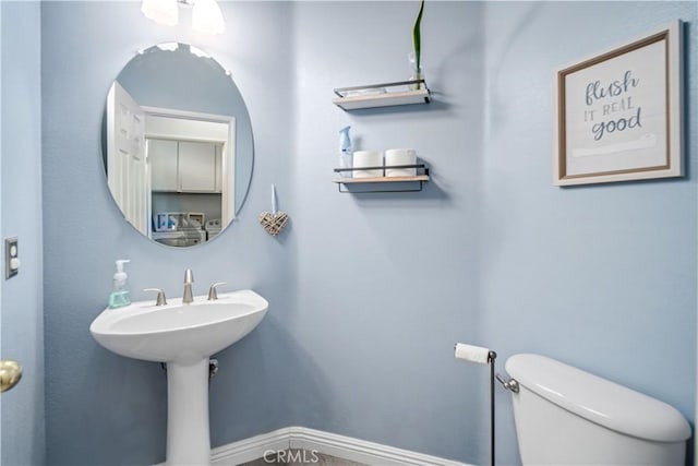 bathroom featuring toilet, a sink, and baseboards