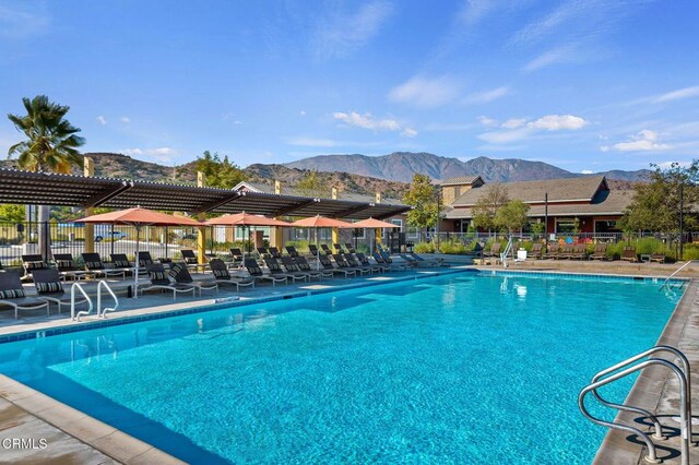 view of pool featuring fence, a patio area, and a mountain view
