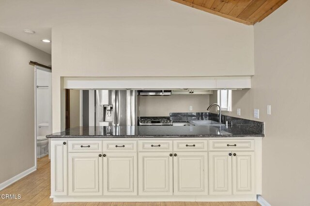 276 Highland Dr, Oxnard, CA 93035 - kitchen with a sink, dark stone countertops, baseboards, light wood finished floors, and a peninsula