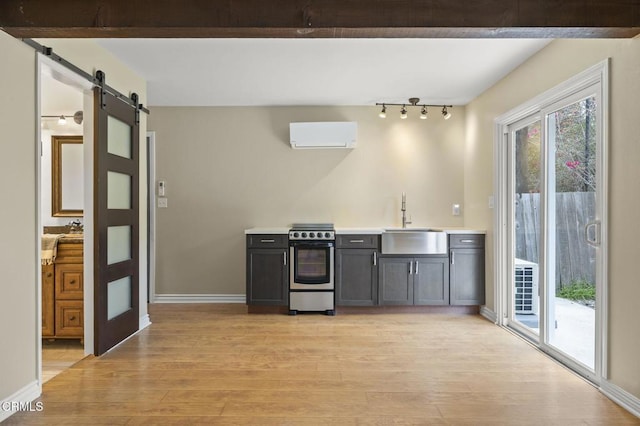 276 Highland Dr, Oxnard, CA 93035 - kitchen featuring a sink, stainless steel electric range, an AC wall unit, a barn door, and light wood finished floors
