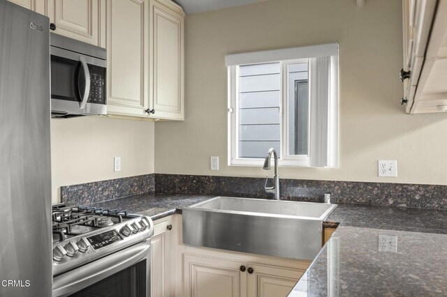 276 Highland Dr, Oxnard, CA 93035 - kitchen with stainless steel appliances, cream cabinetry, a sink, and dark stone counters
