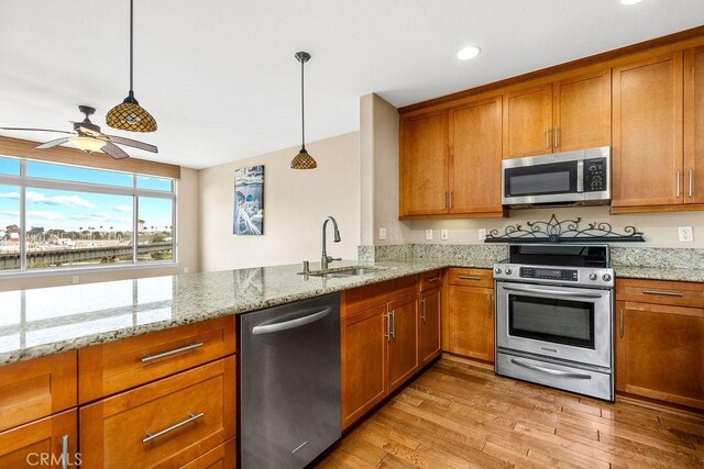 1021 Costa Pacifica Way Unit 2105, Oceanside, CA 92054 - kitchen featuring stainless steel appliances, brown cabinetry, ceiling fan, light wood-type flooring, and light stone counters