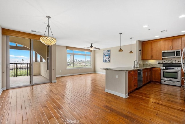 1021 Costa Pacifica Way Unit 2105, Oceanside, CA 92054 - kitchen featuring appliances with stainless steel finishes, a peninsula, brown cabinetry, a ceiling fan, and wood finished floors