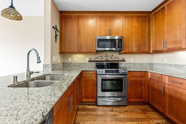 1021 Costa Pacifica Way Unit 2105, Oceanside, CA 92054 - kitchen featuring stainless steel appliances, brown cabinets, wood finished floors, light stone countertops, and decorative light fixtures