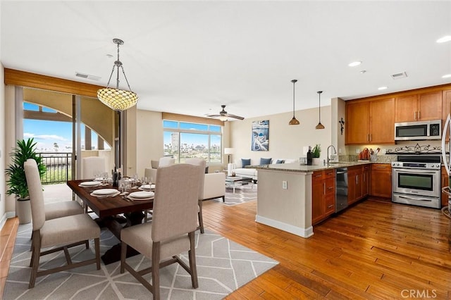 1021 Costa Pacifica Way Unit 2105, Oceanside, CA 92054 - kitchen featuring appliances with stainless steel finishes, a peninsula, hardwood / wood-style floors, brown cabinetry, and ceiling fan