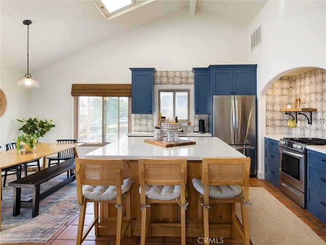 535 E Walnut Ave Unit A, El Segundo, CA 90245 - kitchen featuring stainless steel appliances, blue cabinets, high vaulted ceiling, decorative backsplash, and light countertops