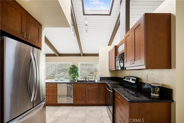 kitchen featuring a sink, brown cabinets, dark stone countertops, light tile patterned floors, and stainless steel appliances