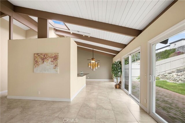 corridor featuring lofted ceiling with skylight, light tile patterned flooring, and baseboards