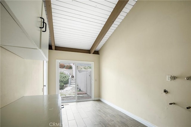 doorway with vaulted ceiling with beams, baseboards, and wood finished floors