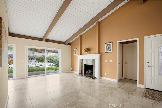 unfurnished living room featuring plenty of natural light, a high end fireplace, beam ceiling, and light tile patterned floors