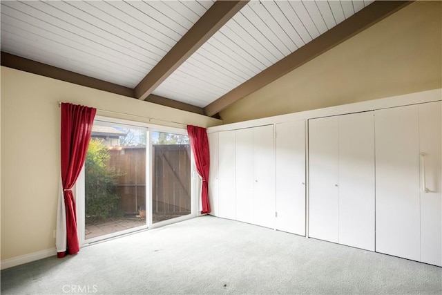 unfurnished bedroom with access to exterior, lofted ceiling with beams, two closets, and carpet
