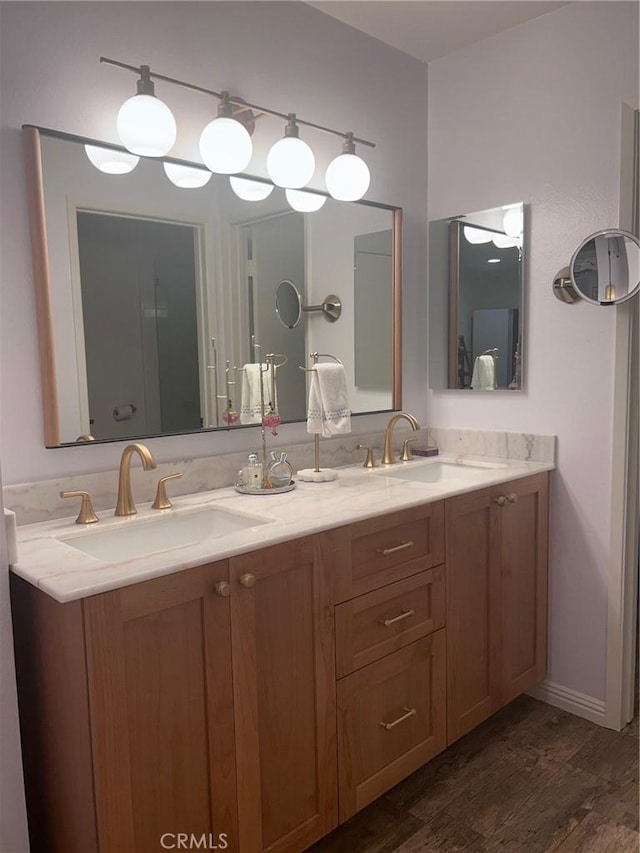 full bath featuring double vanity, a sink, and wood finished floors