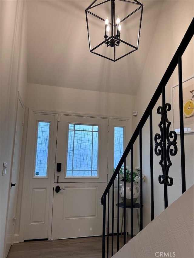 entrance foyer with an inviting chandelier, wood finished floors, and stairs