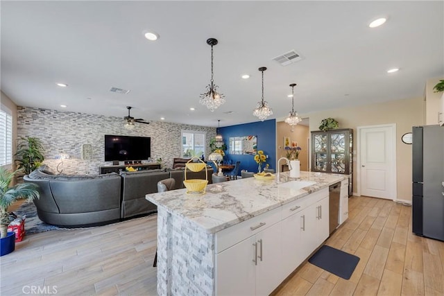 kitchen with stainless steel appliances, ceiling fan with notable chandelier, a sink, visible vents, and white cabinets