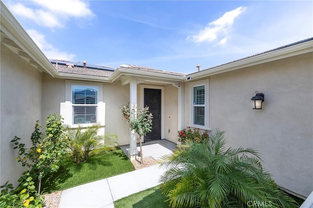 view of exterior entry with solar panels and stucco siding