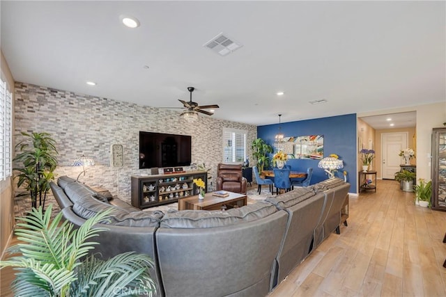 living area featuring light wood-style flooring, baseboards, ceiling fan with notable chandelier, visible vents, and recessed lighting