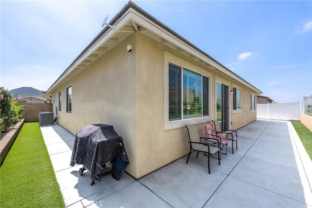 rear view of house featuring cooling unit, a fenced backyard, stucco siding, and a patio