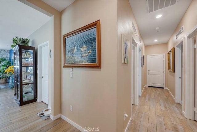hallway featuring baseboards, visible vents, and light wood-type flooring