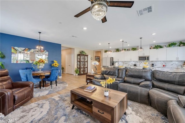living area featuring ceiling fan with notable chandelier, visible vents, light wood-style flooring, and recessed lighting