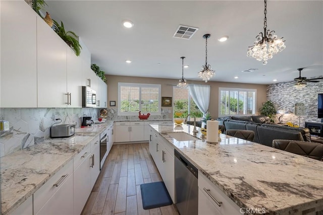 kitchen with open floor plan, stainless steel appliances, backsplash, a sink, and visible vents