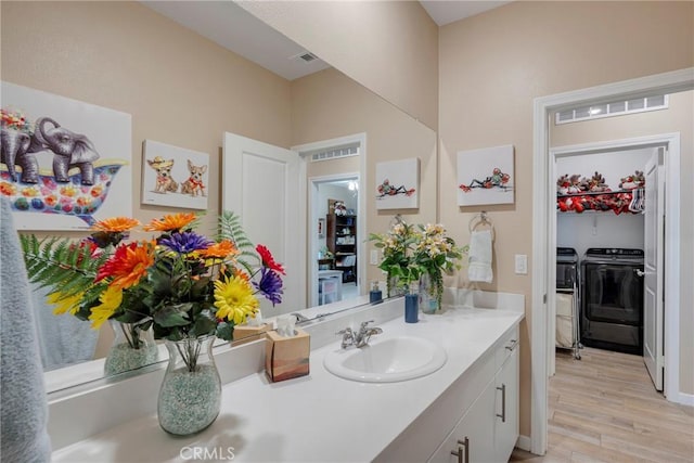 bathroom featuring visible vents, independent washer and dryer, vanity, and wood finished floors