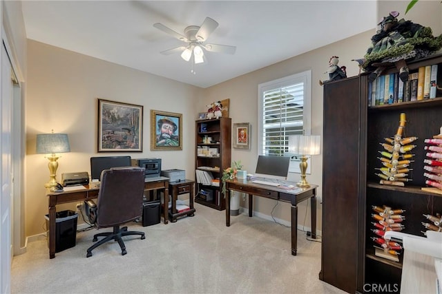 carpeted office space with a ceiling fan and baseboards
