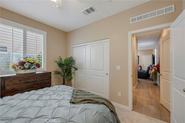 bedroom featuring light wood finished floors, baseboards, visible vents, and a closet