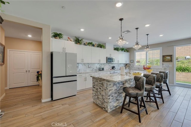 kitchen featuring white cabinetry, a breakfast bar area, backsplash, visible vents, and appliances with stainless steel finishes