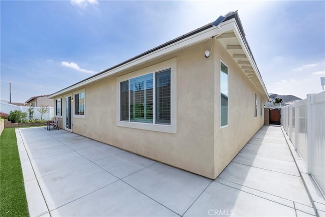 view of side of property with a fenced backyard, stucco siding, and a patio