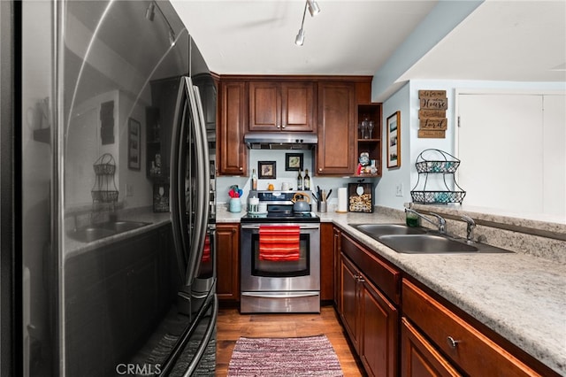 kitchen with a sink, light countertops, stainless steel range with electric stovetop, under cabinet range hood, and light wood finished floors