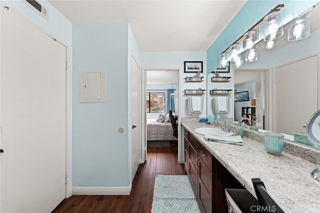 bathroom with wood finished floors, ensuite bath, vanity, baseboards, and visible vents