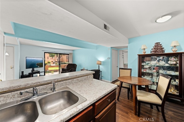 kitchen featuring dark wood finished floors, light countertops, a sink, visible vents, and open floor plan