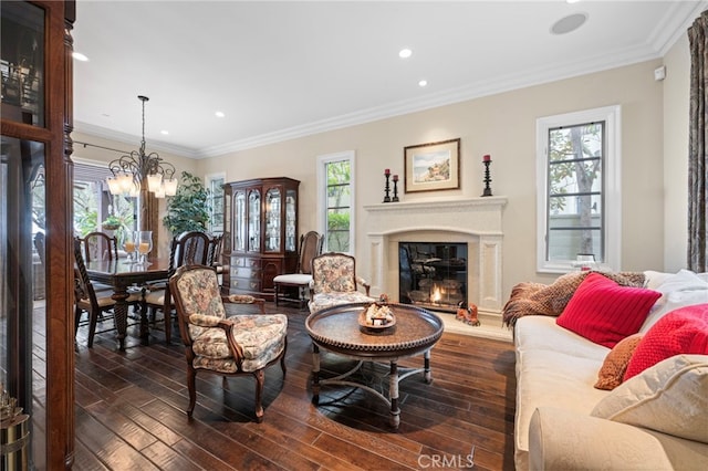 living room with wood-type flooring, plenty of natural light, a notable chandelier, and a glass covered fireplace
