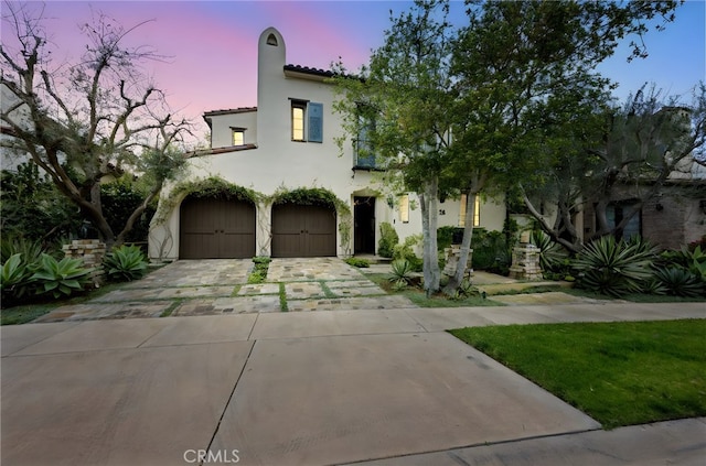 mediterranean / spanish home with an attached garage, concrete driveway, stucco siding, and a tile roof