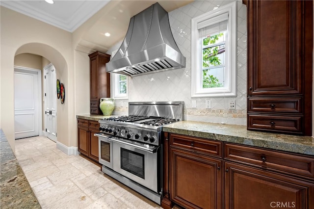 28 Surfspray Blf, Newport Coast, CA 92657 - kitchen with double oven range, wall chimney range hood, stone tile floors, crown molding, and arched walkways