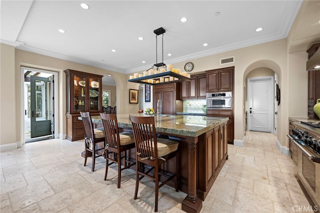 28 Surfspray Blf, Newport Coast, CA 92657 - kitchen featuring arched walkways, stone tile flooring, a large island with sink, recessed lighting, and premium appliances