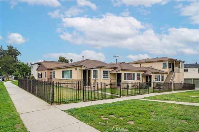 view of front facade featuring stucco siding, a fenced front yard, a front yard, and a residential view