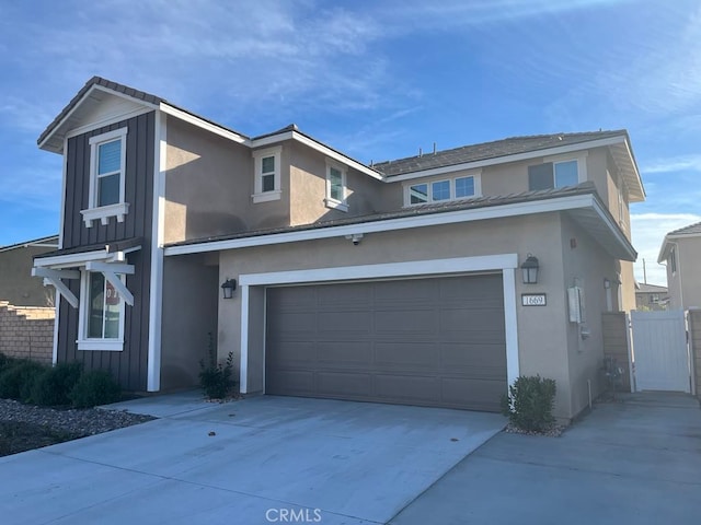 traditional home featuring a gate, stucco siding, concrete driveway, and board and batten siding
