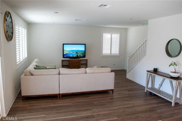 living area with visible vents, plenty of natural light, wood finished floors, and stairway